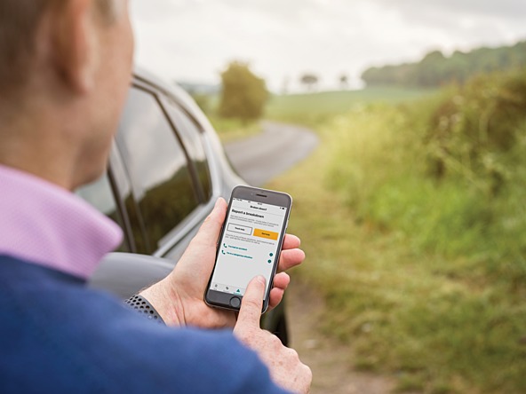 Man next to car uses AA app by roadside