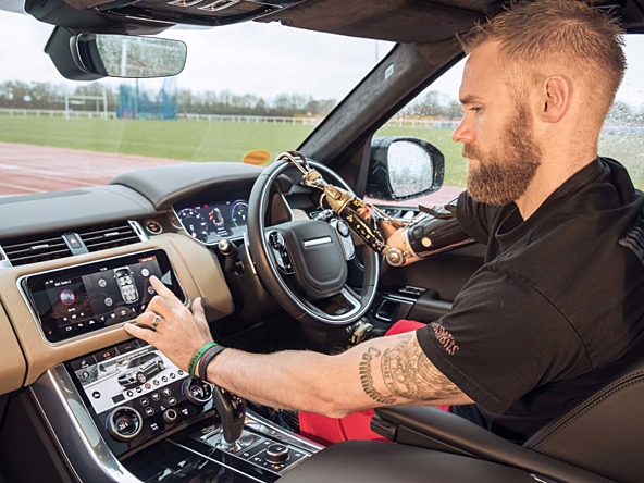 Man with prosthetic arm driving Land Rover
