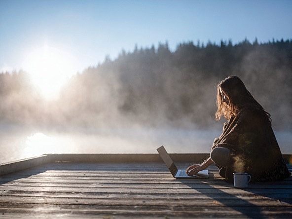 Woman remote working next to lake